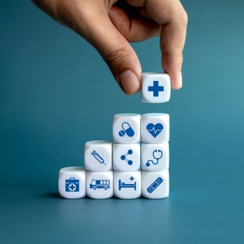 Healthcare medical, wellness plan and insurance concept. Health, care and medical element icon symbols on clean white blocks stacking as a graph arranged by doctor's hand on blue background.